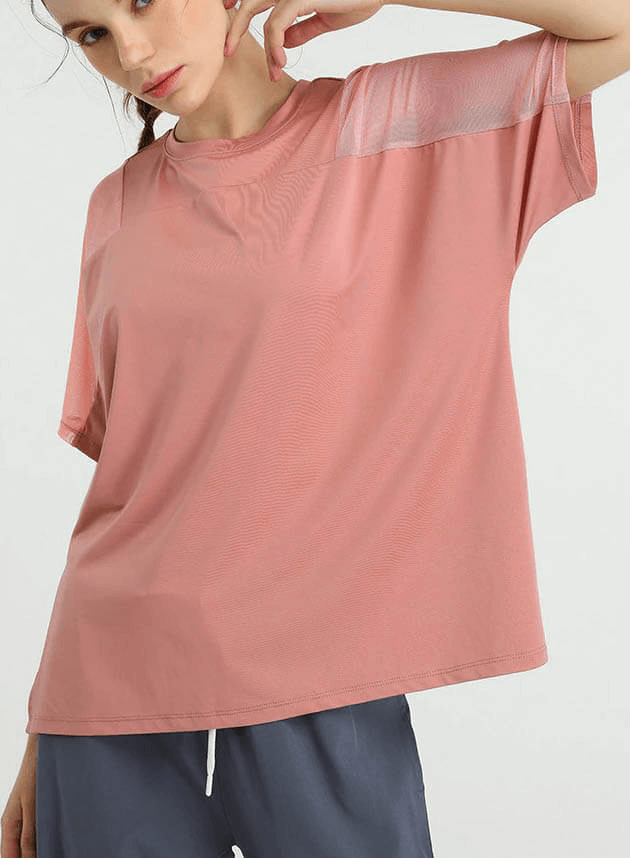Woman wearing a loose pink mesh short sleeves t-shirt, ideal for workout and running, showcasing breathable and quick-dry fabric.